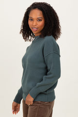 woman wearing a dark green knit sweater with dropped shoulders and a relaxed fit