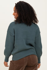 woman wearing a teal oversized sweater with ribbed details, styled with brown corduroy pants