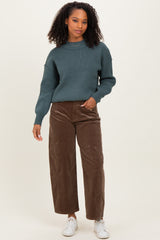 woman wearing a dark teal knitted sweater and brown wide-leg corduroy pants with white sneakers