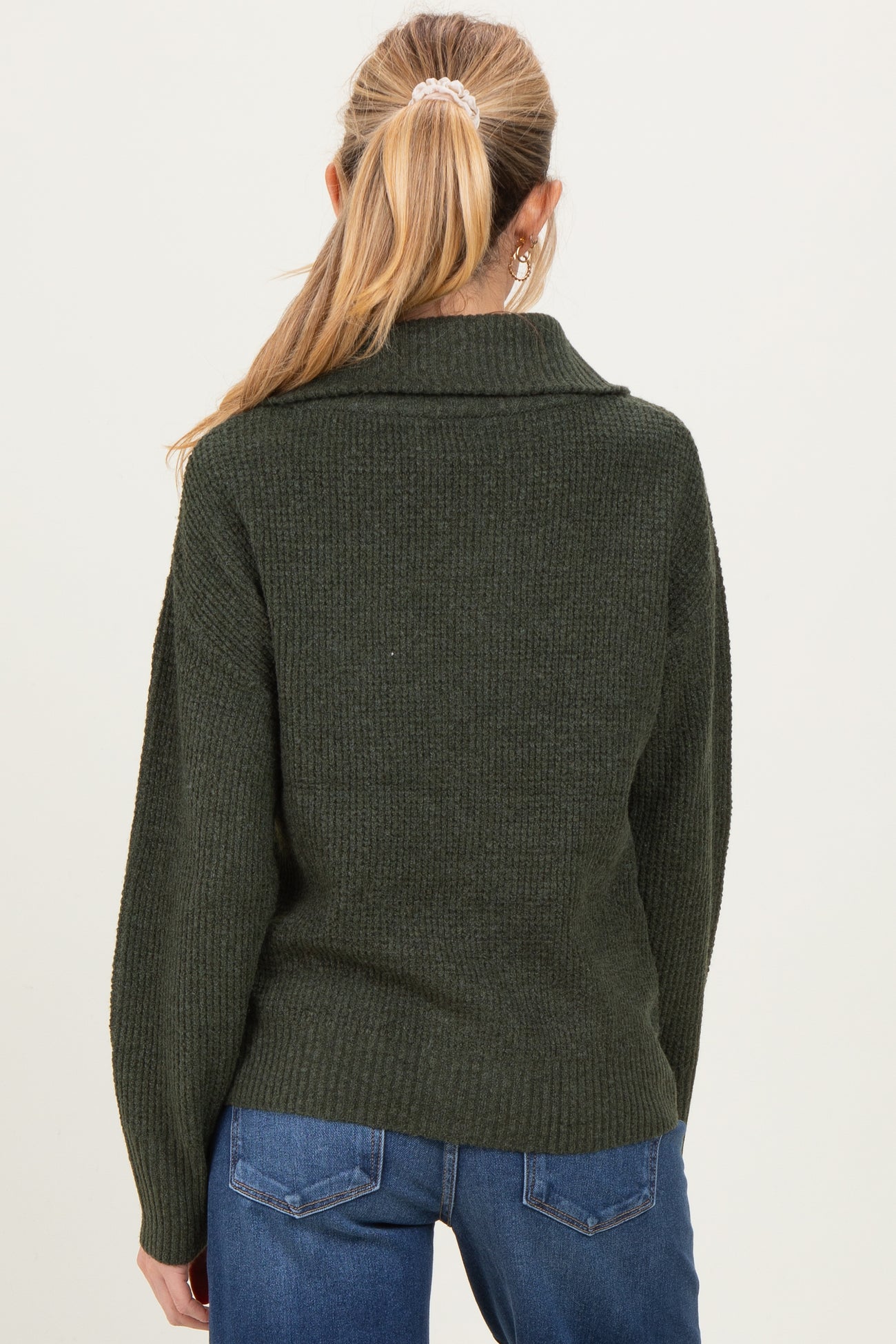 woman wearing a dark green oversized maternity sweater with a ribbed texture, showing the back view