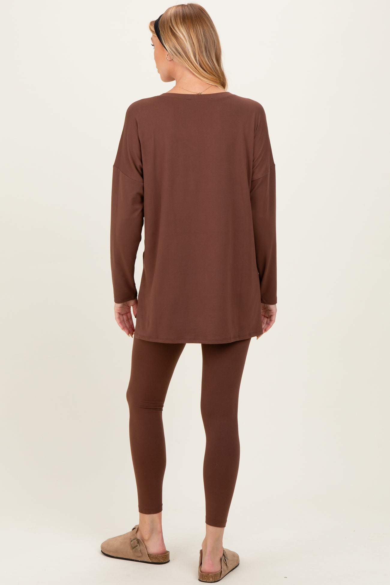 woman wearing a brown maternity long sleeve tunic and matching leggings, styled with casual slip-on shoes