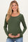 woman wearing a dark green long sleeve maternity top and holding her baby bump
