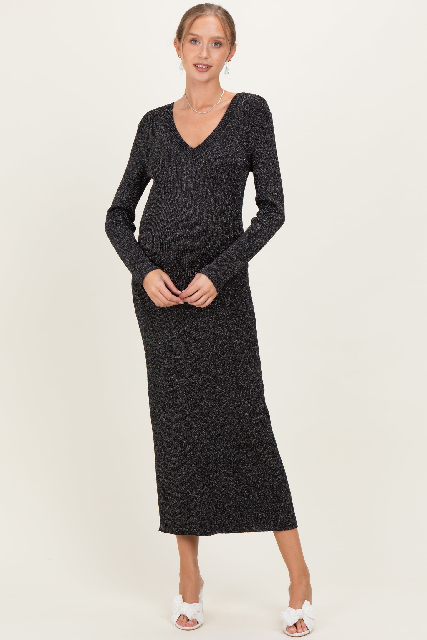 woman wearing a dark shimmer knit maternity dress with a v-neck and long sleeves, showing her baby bump