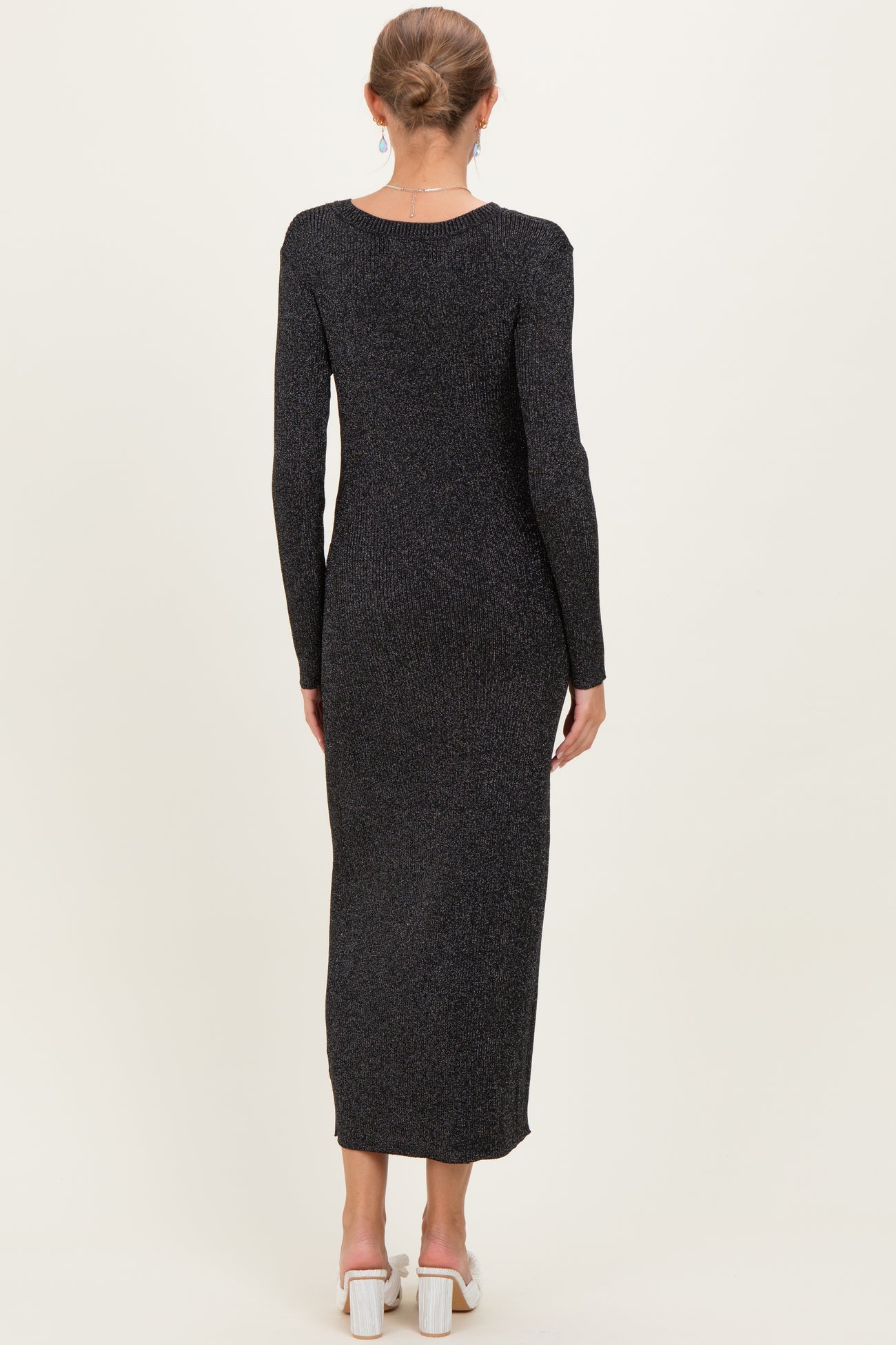 woman wearing a black long sleeve ribbed maternity dress, showing a sleek back view and floor-length style