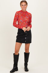woman wearing a red floral long sleeve top paired with a black denim mini skirt and knee-high black boots