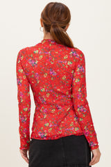 woman wearing a red long sleeve floral top, view from the back with colorful floral patterns