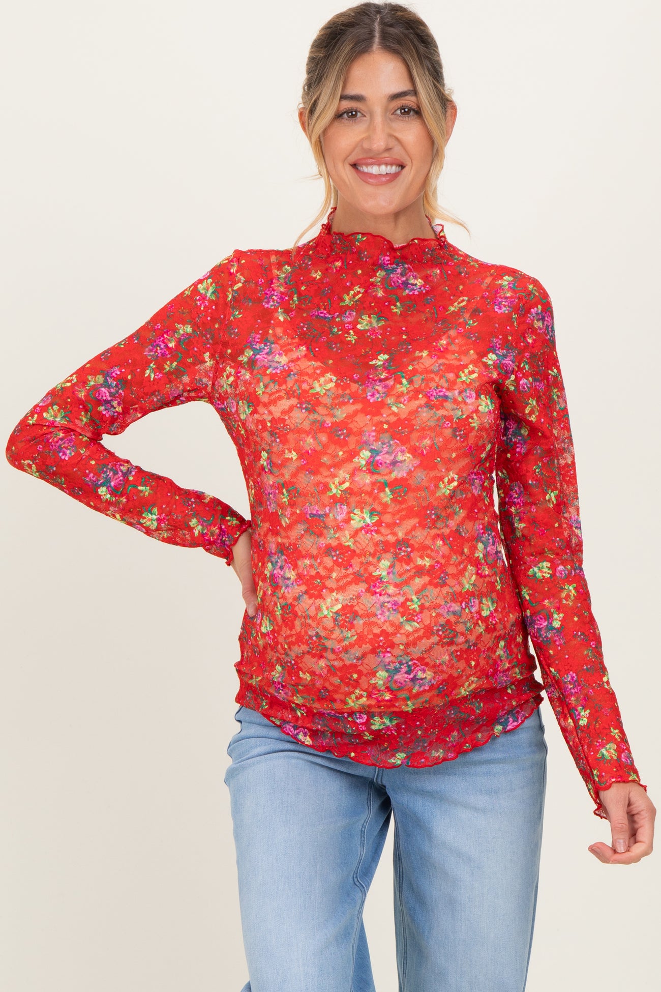 woman wearing a red floral long sleeve maternity top that highlights her baby bump