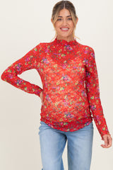 woman wearing a red floral long sleeve maternity top that highlights her baby bump