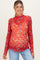 woman wearing a red floral maternity top with long sleeves and scalloped neckline, showcasing her baby bump