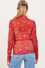 woman wearing a red floral maternity top with long sleeves, viewed from the back, paired with blue jeans