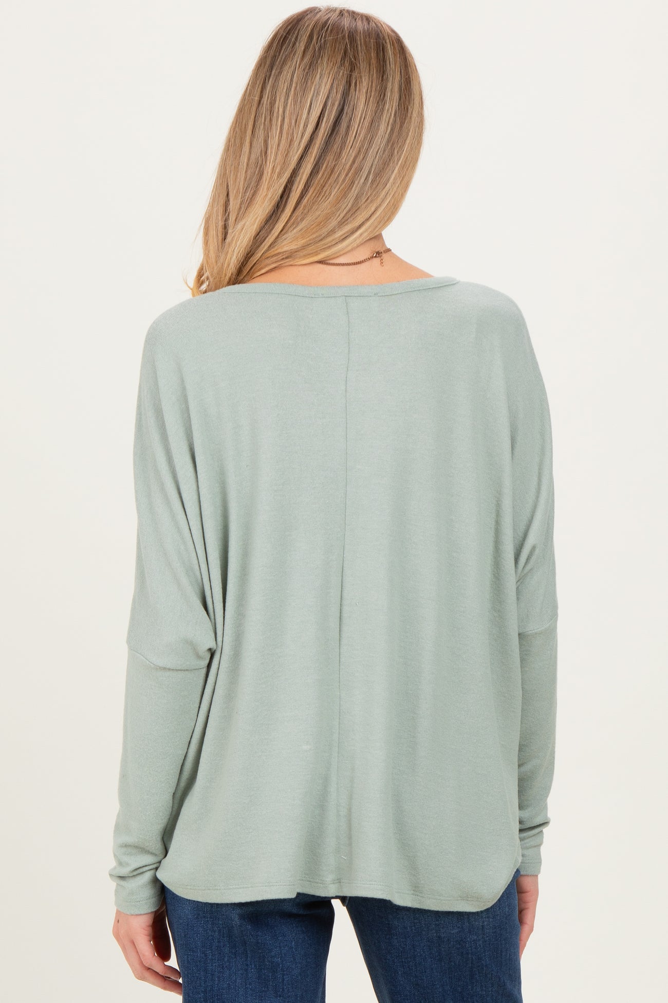woman wearing a light green maternity top with a relaxed fit and long sleeves, viewed from the back
