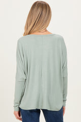 woman wearing a light green maternity top with a relaxed fit and long sleeves, viewed from the back