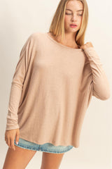 woman wearing a beige oversized long sleeve top with a relaxed fit and denim shorts