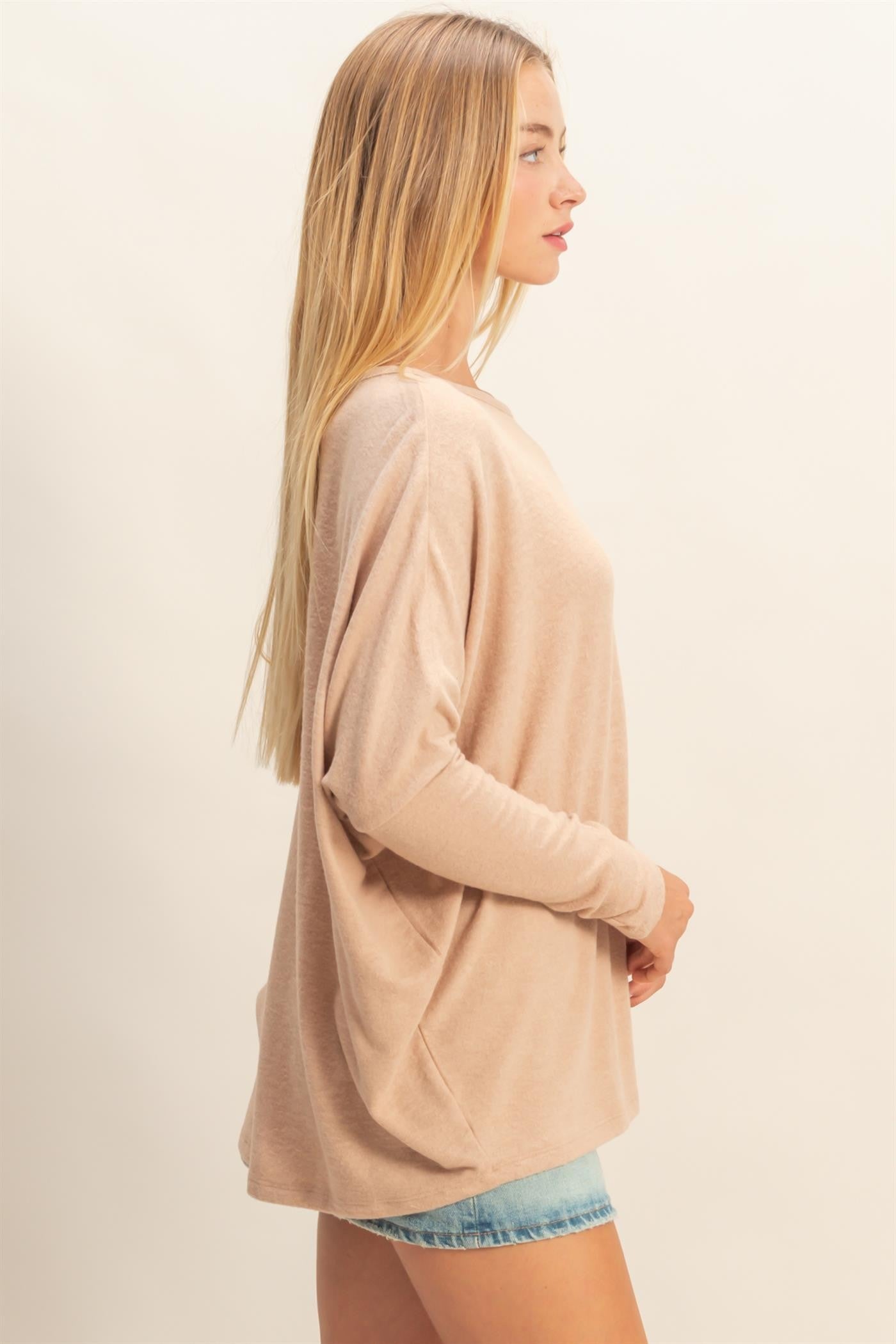 woman wearing a light beige oversized long sleeve top with a relaxed fit and casual shorts