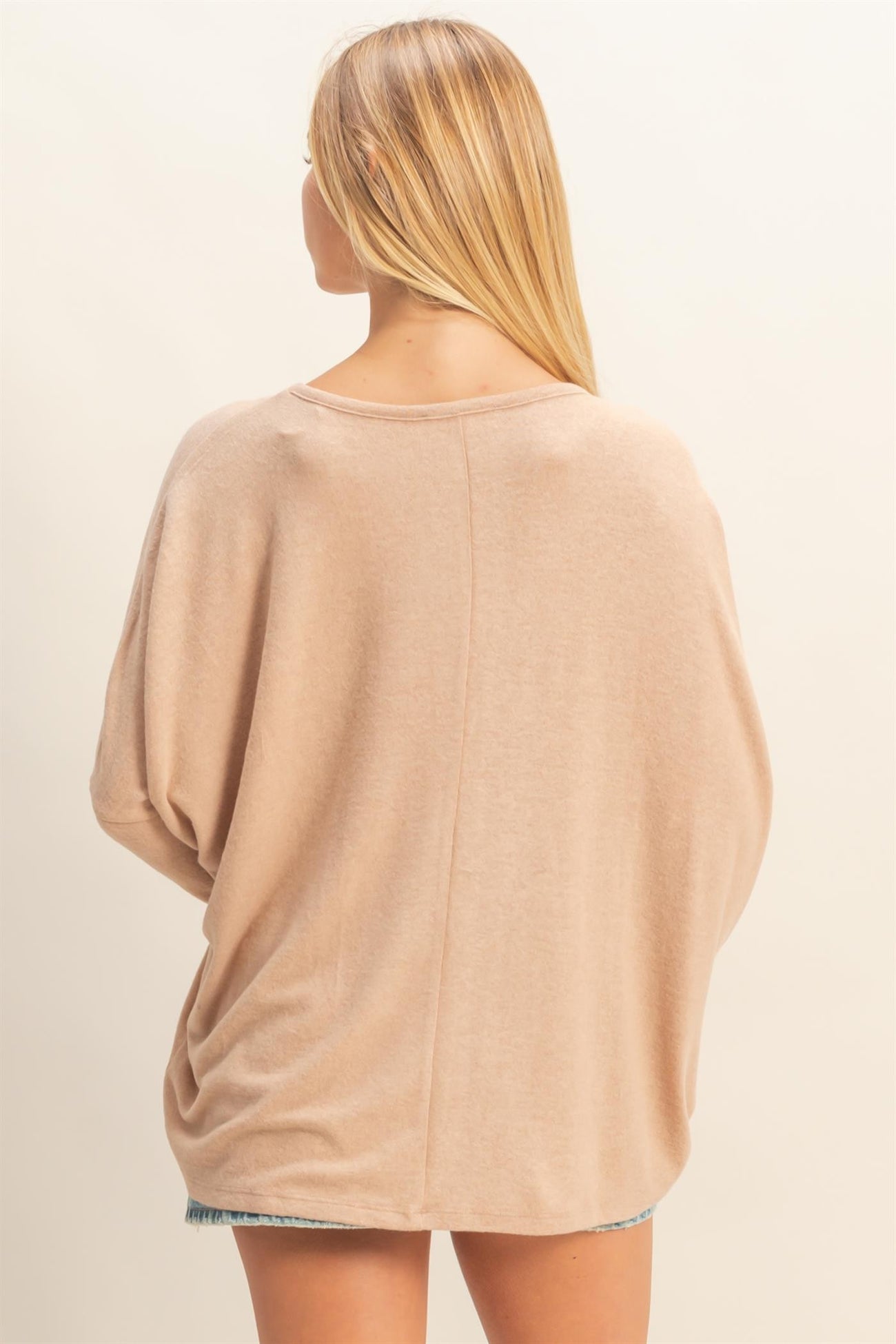 woman wearing a beige oversized sweater with a relaxed fit and scoop neckline, shown from the back