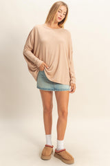 woman wearing a beige oversized sweater with a loose fit and denim mini skirt, paired with cozy slip-on shoes