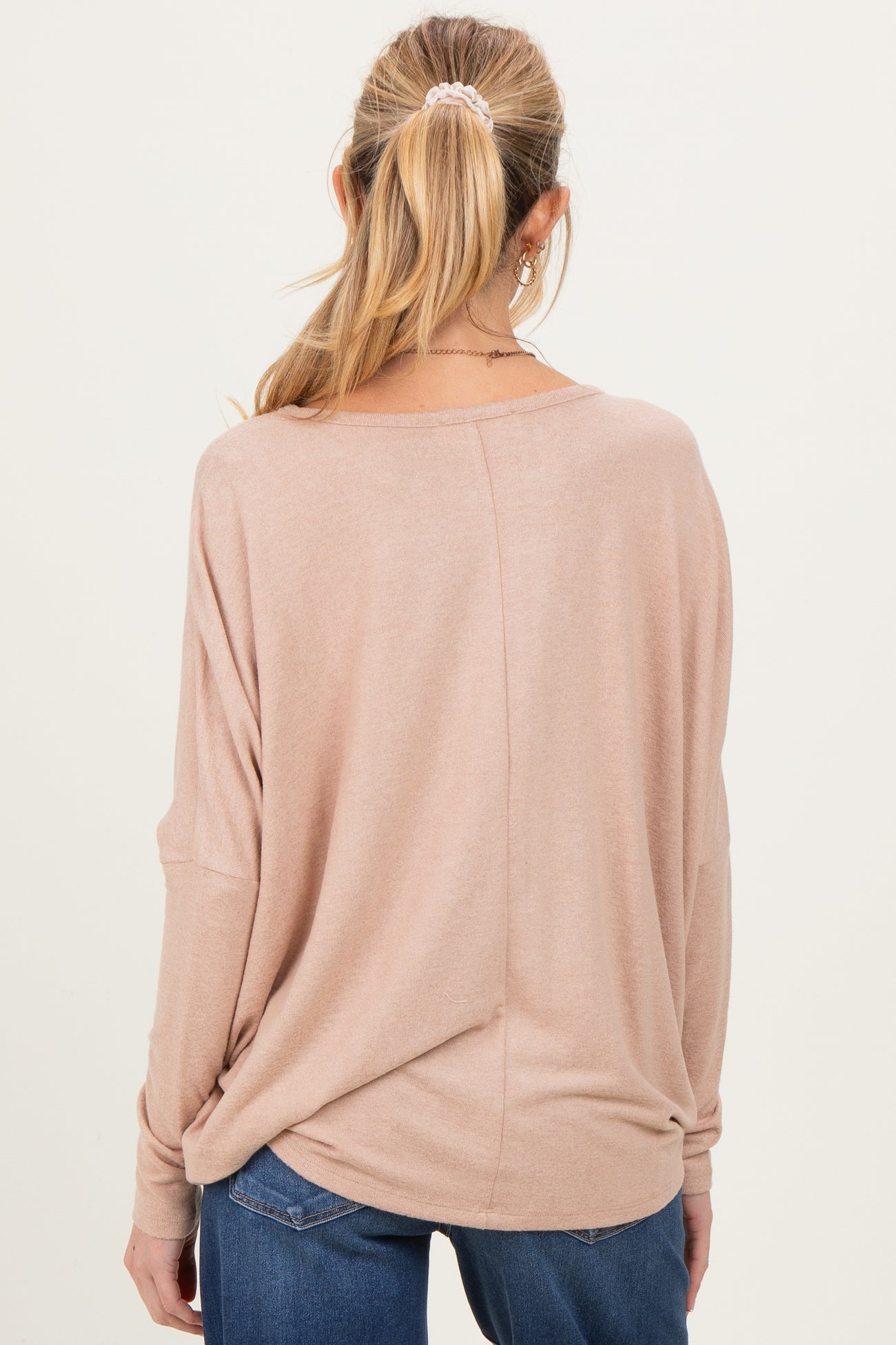 woman wearing a soft pink oversized maternity top, highlighting the relaxed fit and back view