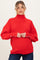 woman wearing a bright red maternity sweater with a high neckline and button details on the sleeves