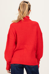 woman wearing a red oversized maternity sweater with ribbed texture and button details on the sleeves