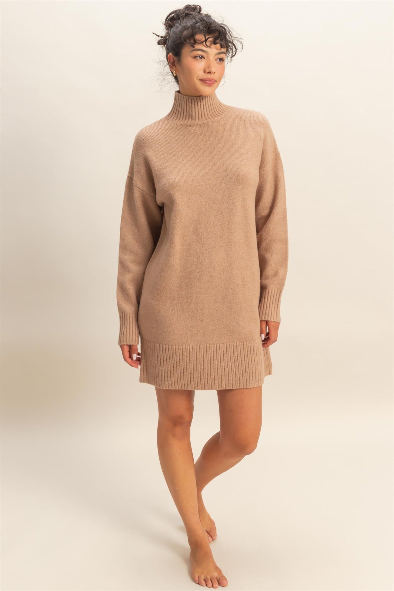 woman wearing a beige knit sweater dress with a high neckline and ribbed hem
