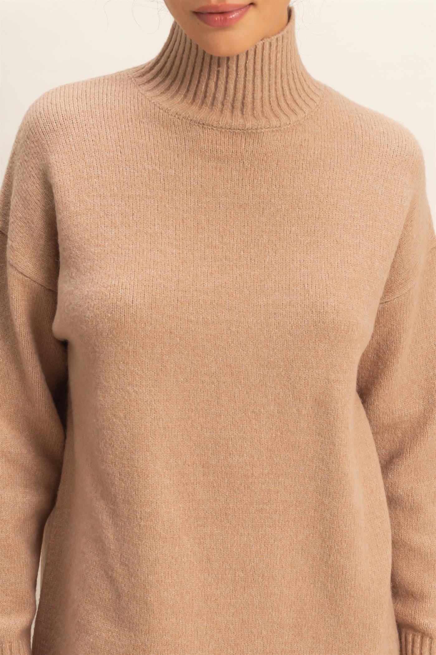 woman wearing a beige turtleneck sweater with ribbed collar and relaxed fit
