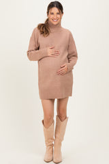 woman wearing a cozy beige turtleneck sweater dress, showing her baby bump, paired with knee-high beige boots
