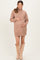 woman wearing a cozy beige turtleneck sweater dress, showing her baby bump, paired with knee-high beige boots