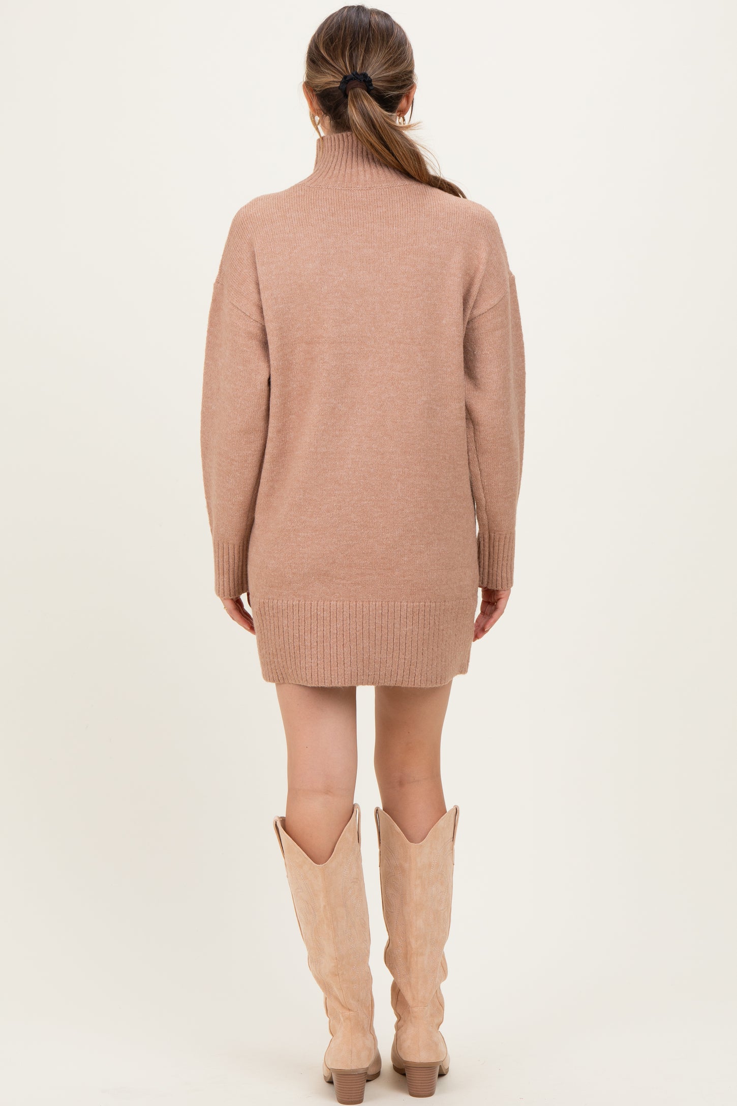 woman wearing a beige maternity sweater dress with a high collar and ribbed hem, showcasing a relaxed fit