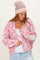 woman wearing a colorful oversized knitted cardigan and a pink beanie, styled with a white tank top and light blue jeans