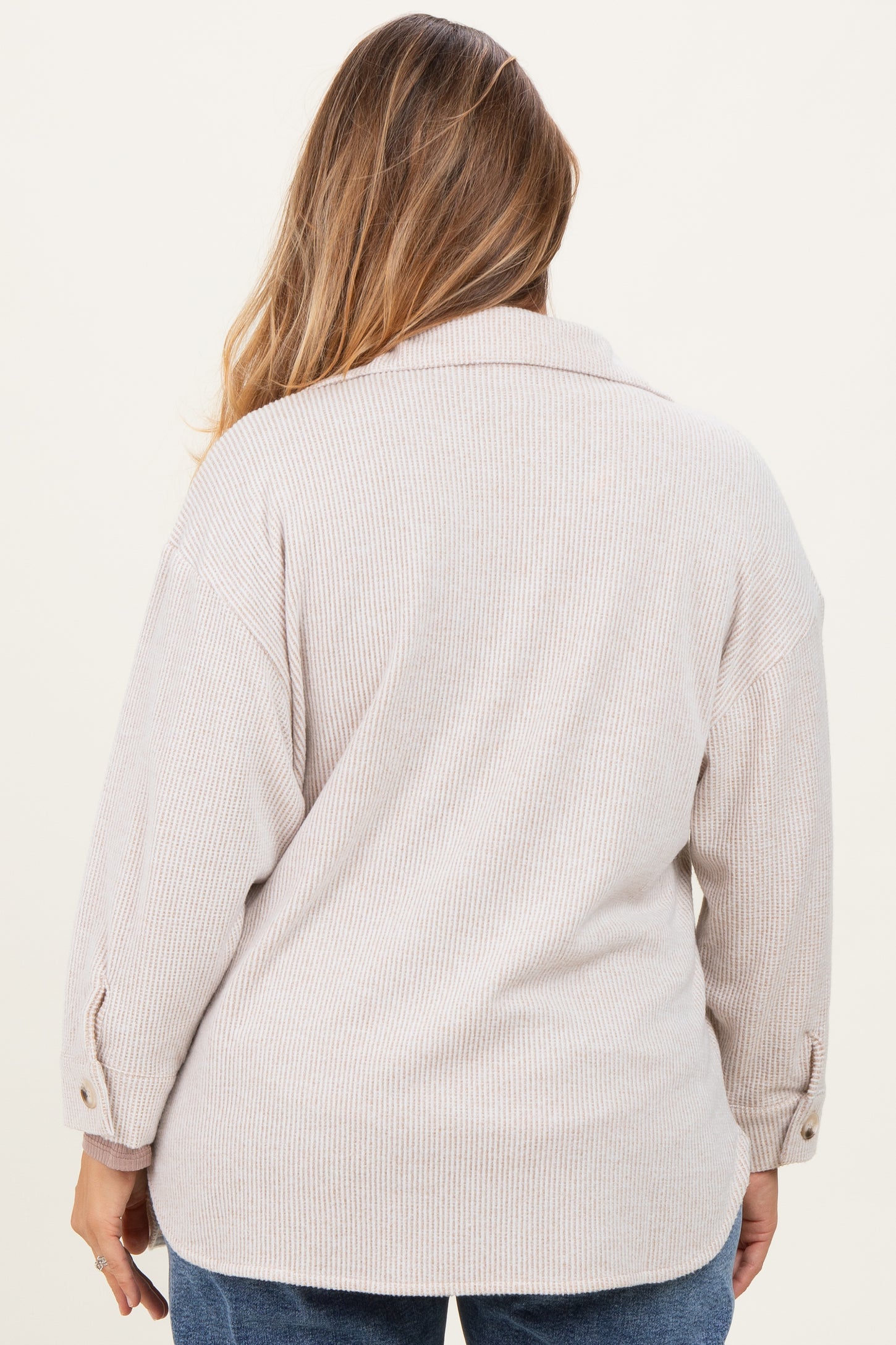 woman wearing a soft beige maternity plus shirt with a relaxed fit and button details on the sleeves, shown from the back
