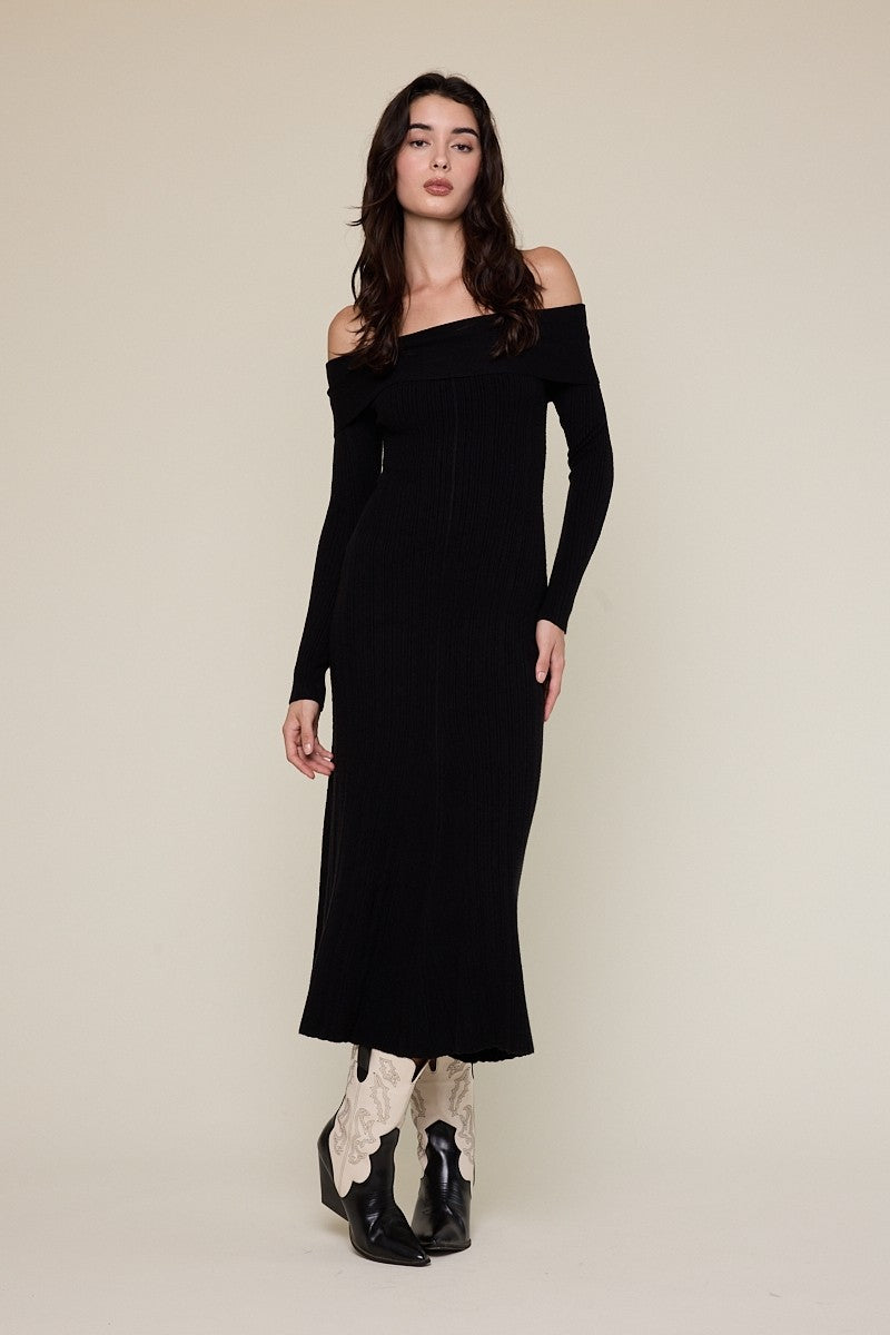 woman wearing a black off-the-shoulder ribbed maxi dress and black ankle boots