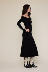 woman wearing a black ribbed off-shoulder maxi dress paired with white floral-embroidered cowboy boots