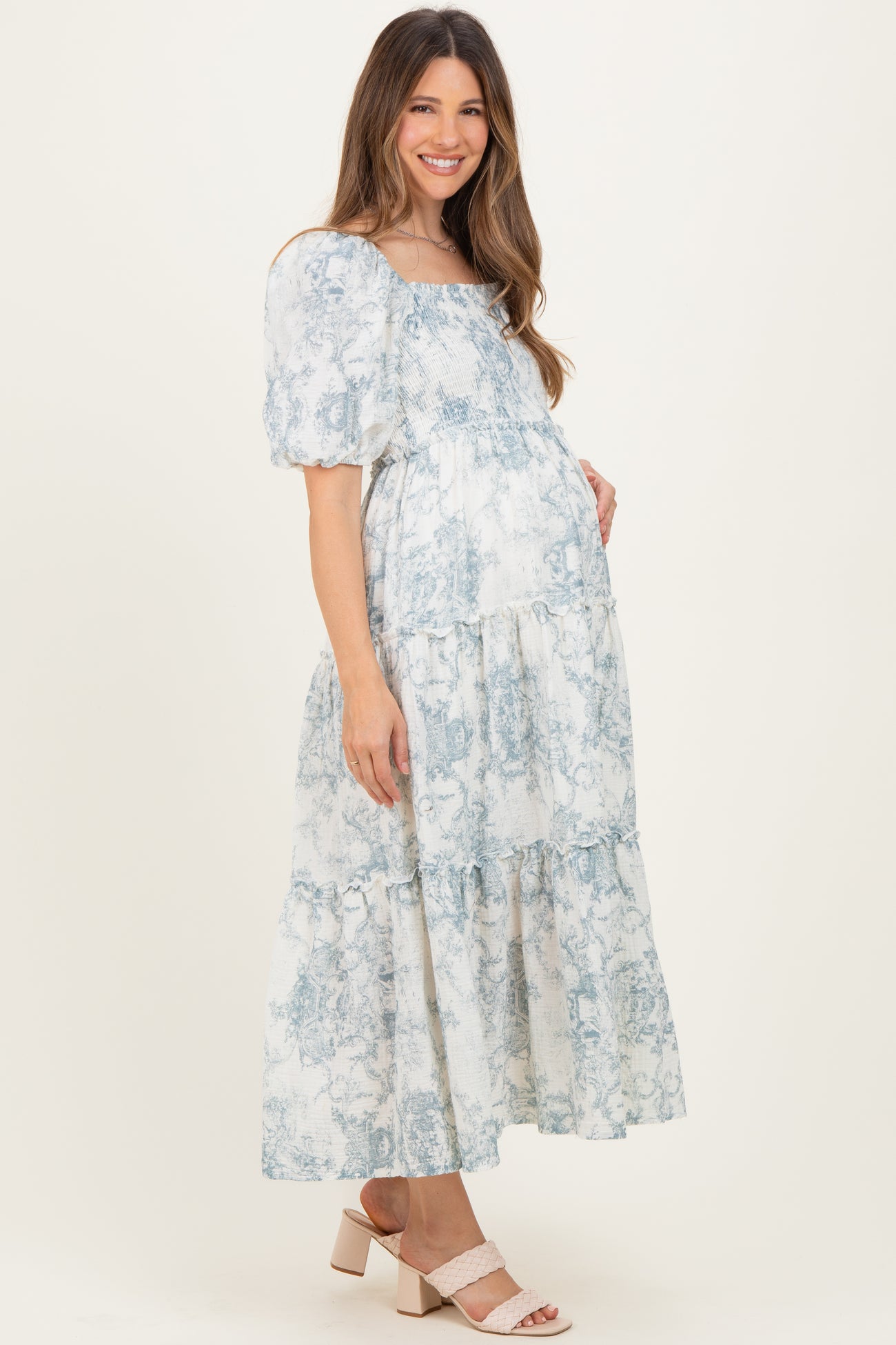 woman wearing a blue and white floral print maternity maxi dress with puff sleeves and a visible baby bump