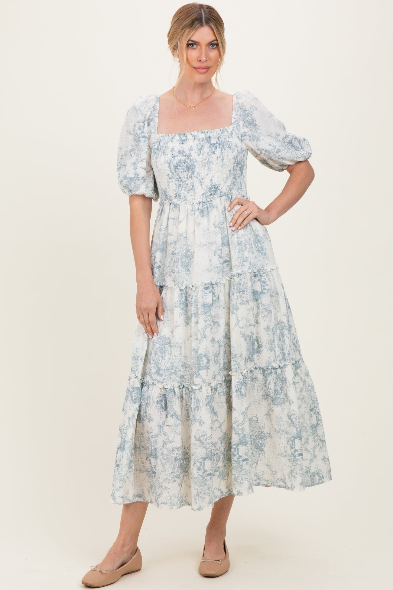 woman wearing a blue and white floral maxi dress with puff sleeves and a square neckline