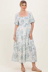 woman wearing a light blue floral maxi dress with puff sleeves and tiered ruffles