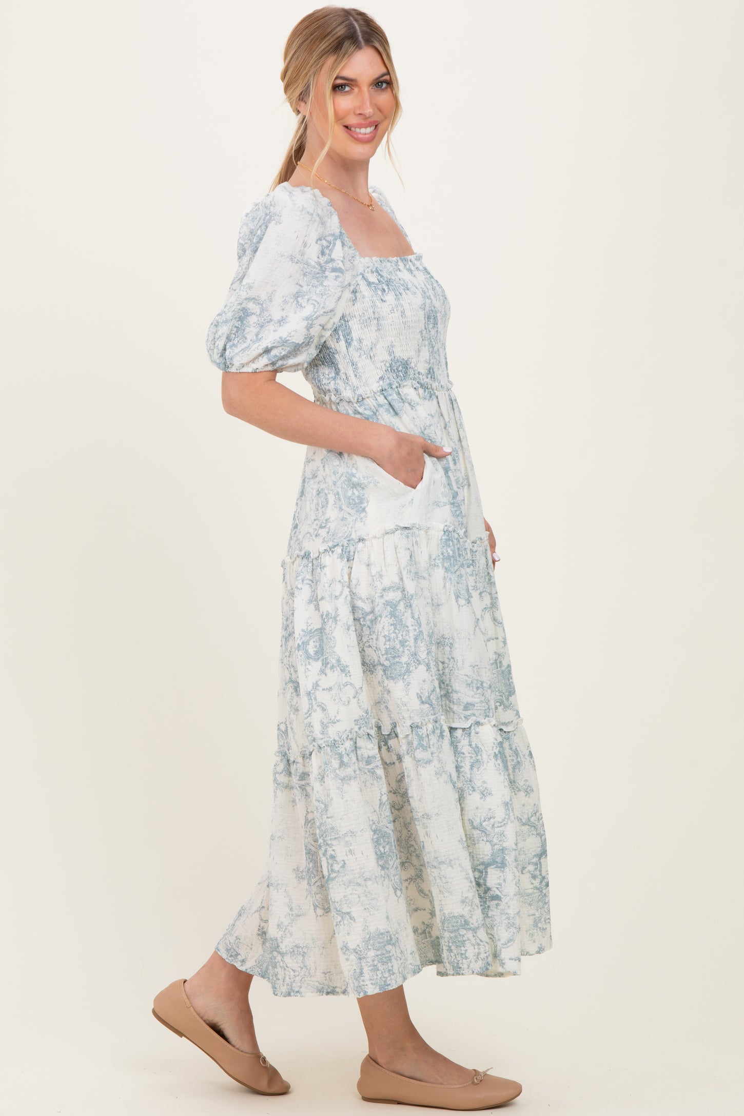 woman wearing a light blue puff sleeve smocked maxi dress with a tiered skirt and side pockets