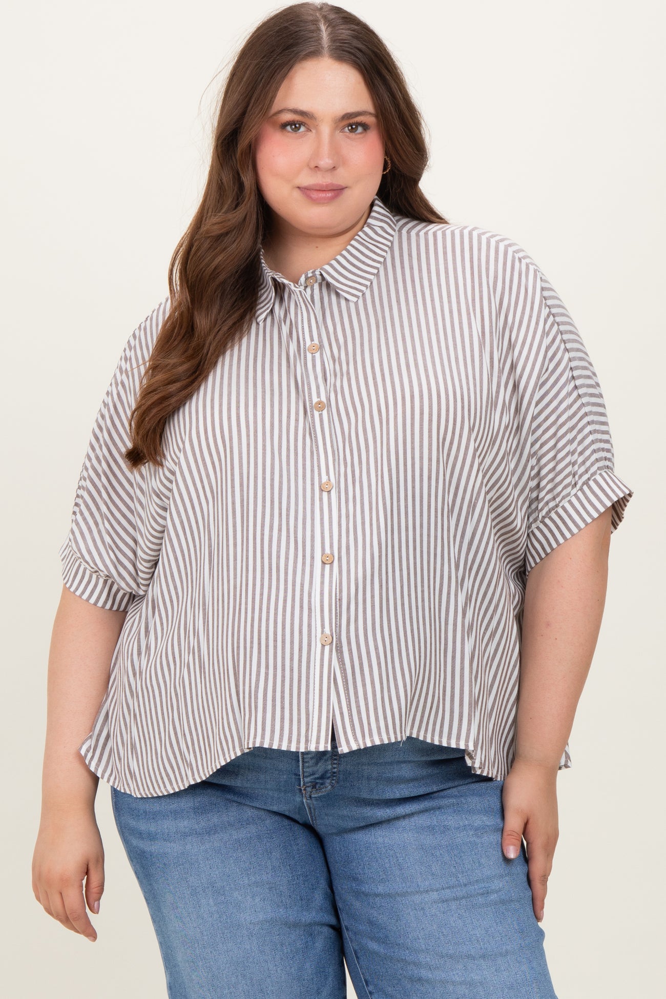 woman wearing a striped short sleeve button-up maternity plus top with a relaxed fit and roll-up sleeves