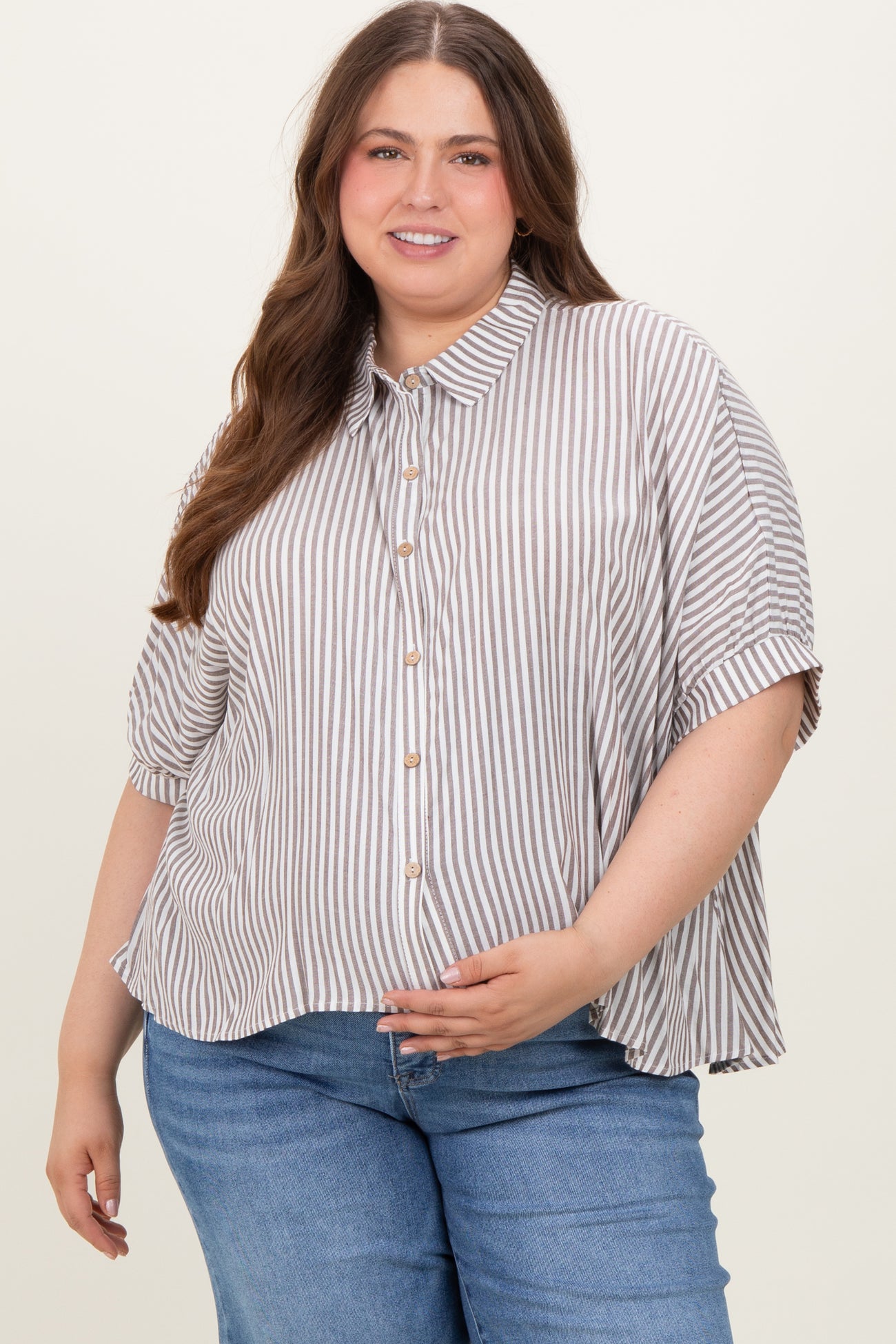 woman wearing a striped button-up maternity top with loose fit and short sleeves, showcasing her baby bump