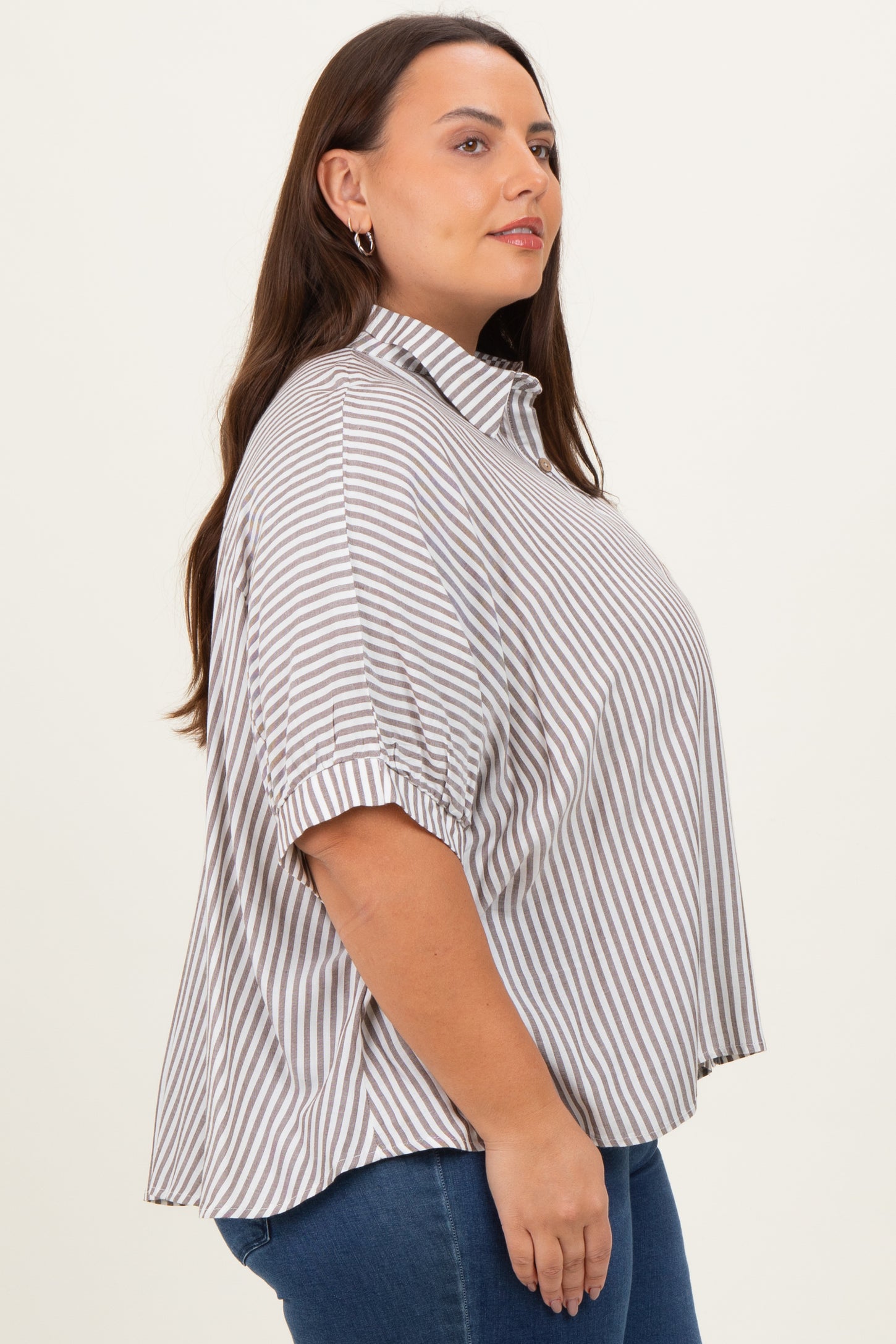woman wearing a brown and white striped plus size shirt with a collar and short sleeves, standing sideways
