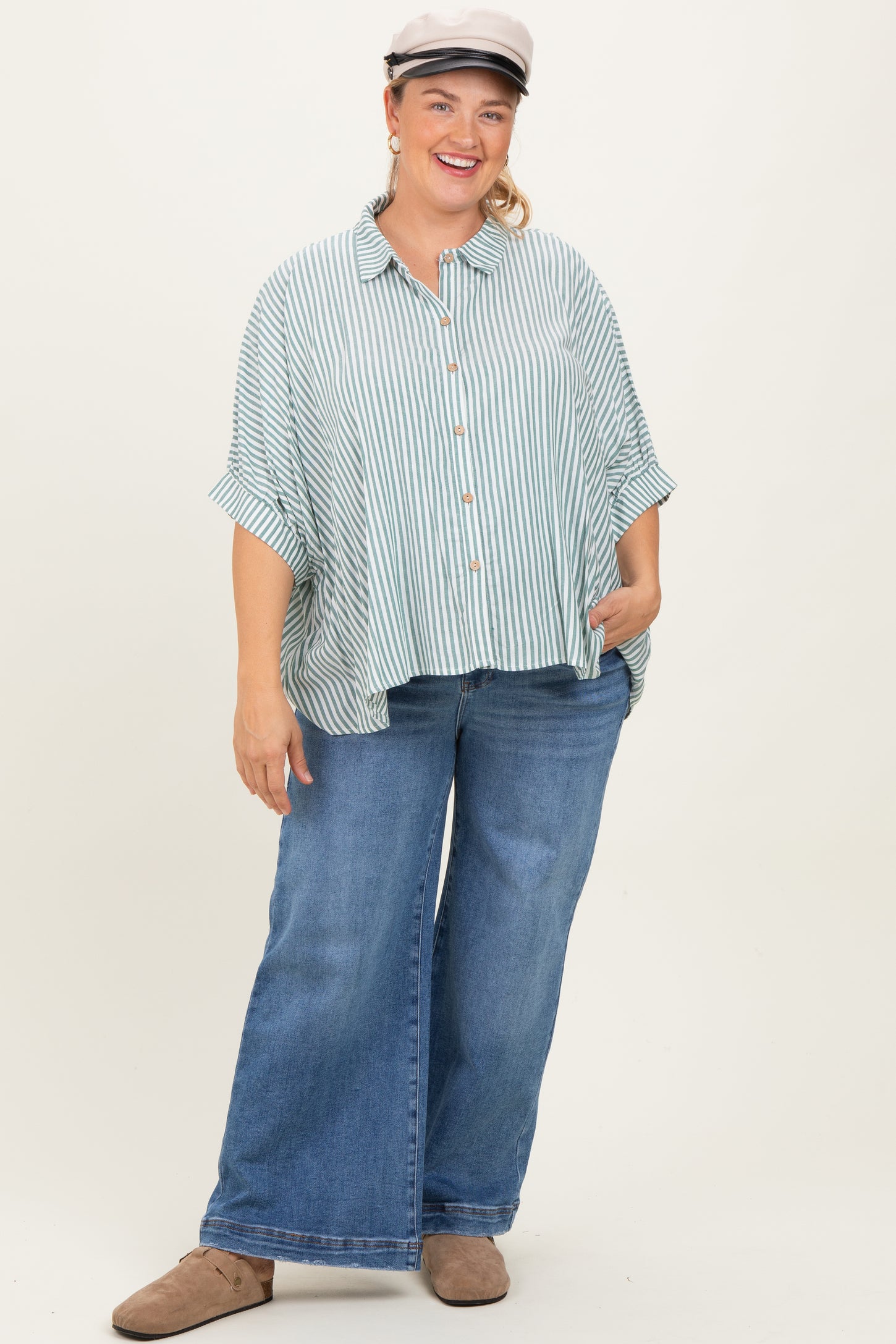 woman wearing a striped maternity plus button-up shirt with loose fit and wide-leg jeans, smiling and posing