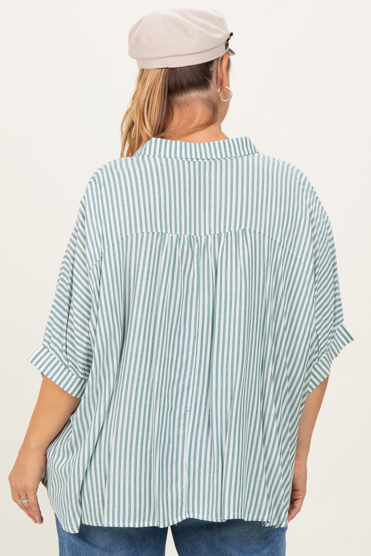 woman wearing a green and white striped maternity plus shirt, featuring a relaxed fit and roll-up sleeves