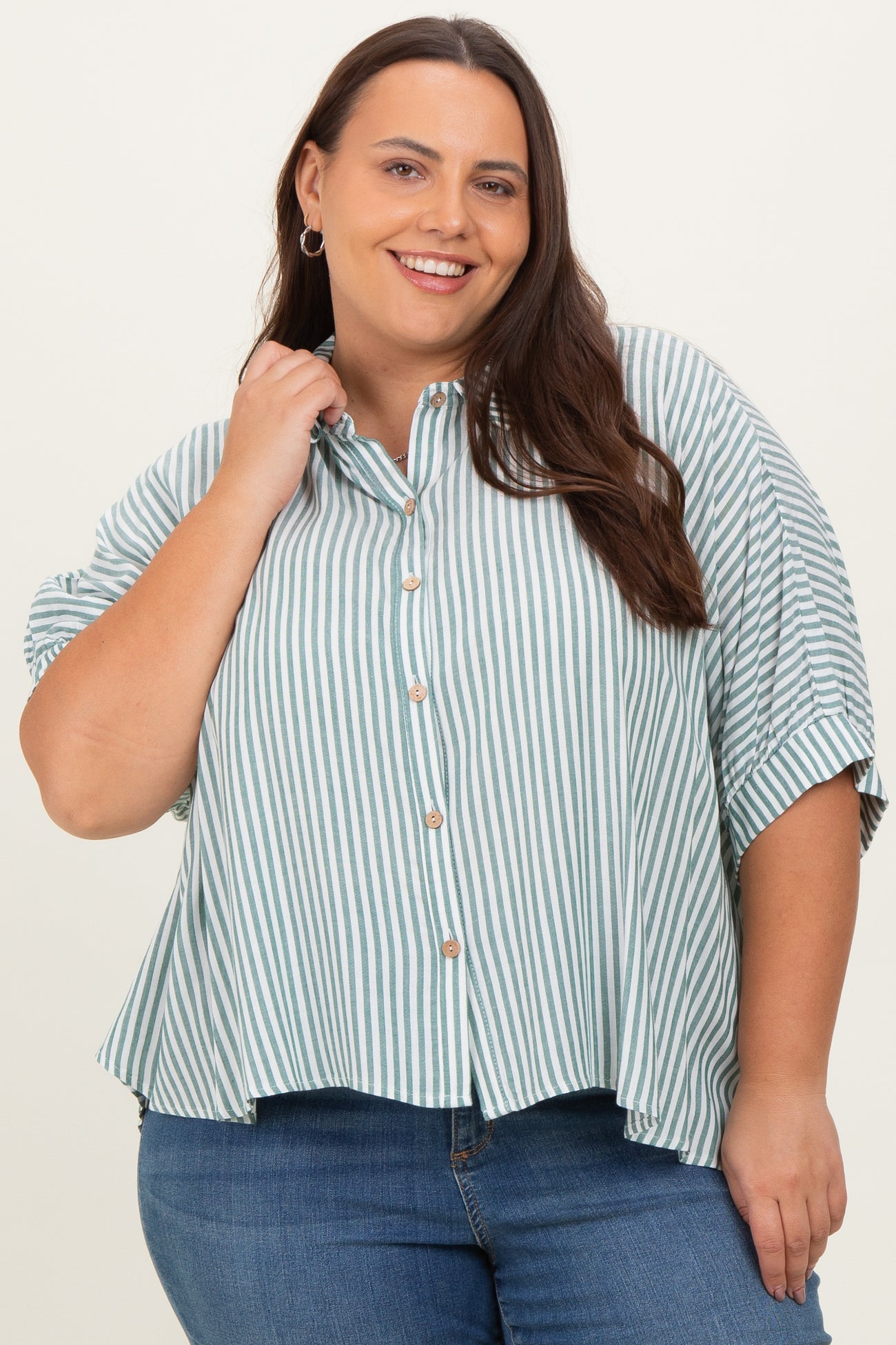 woman wearing a green and white striped plus-size button-up shirt with short sleeves, paired with blue jeans