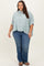 woman wearing a light green and white striped button-up shirt with rolled sleeves and blue jeans