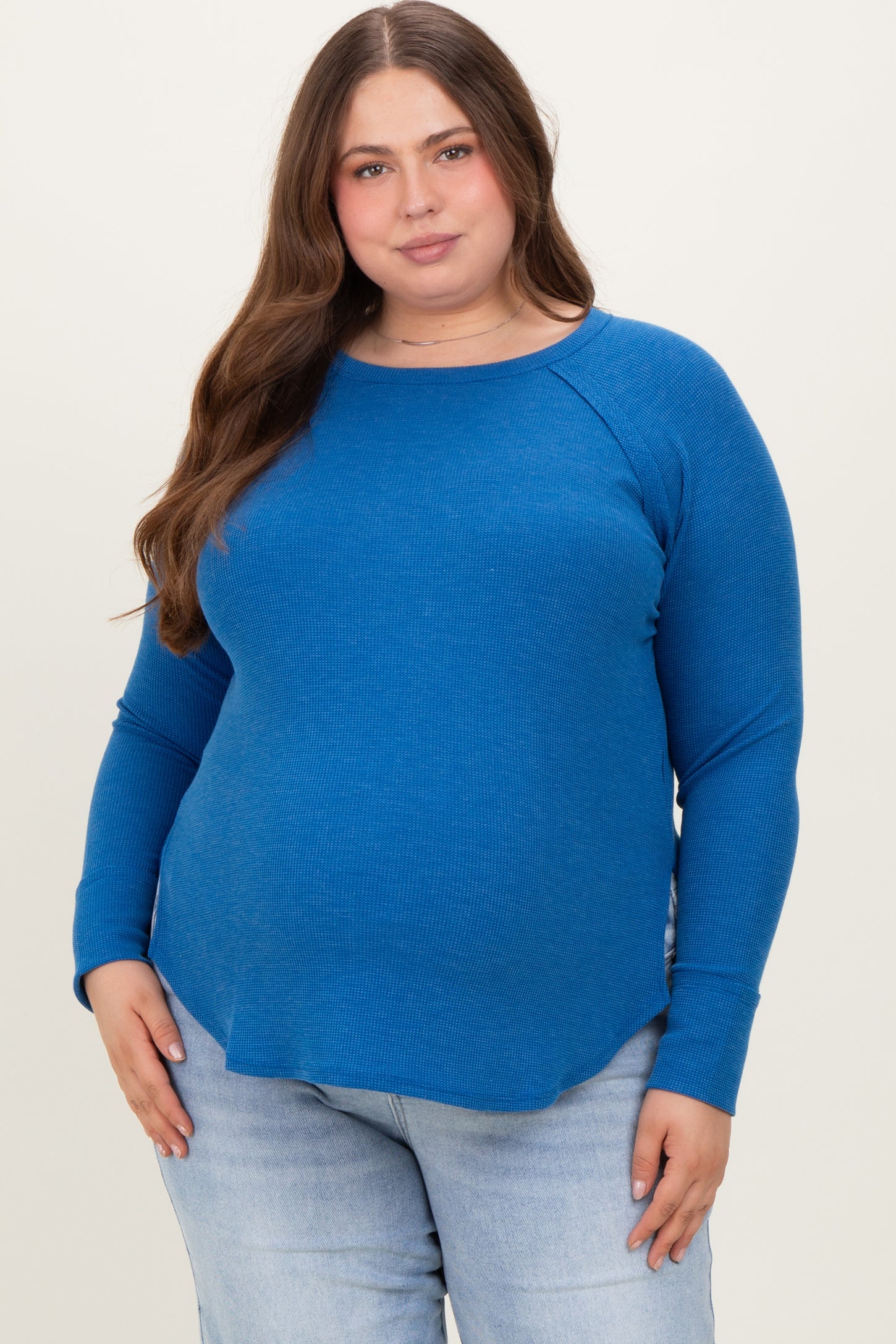 woman wearing a vibrant blue long sleeve maternity top with a curved hem and a visible baby bump