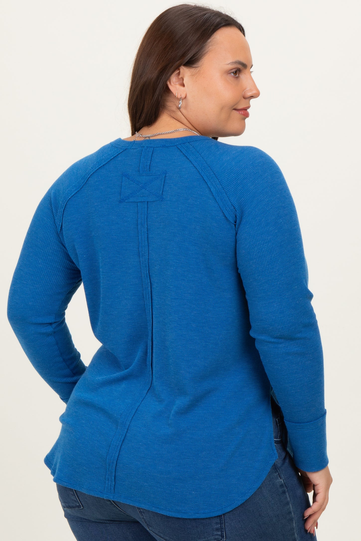 woman wearing a blue long sleeve plus size top with a back seam detail and round neckline