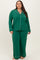 woman wearing a green plus size two-piece pajama set with long sleeves and pants, featuring white piping details