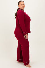 woman wearing a maroon plus size pajama set with white piping details