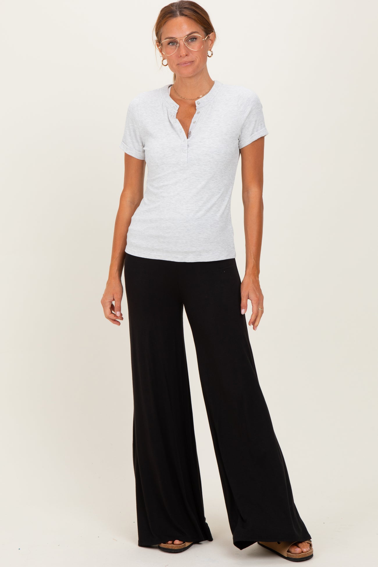 woman wearing a gray short sleeve henley top and black wide-leg pants