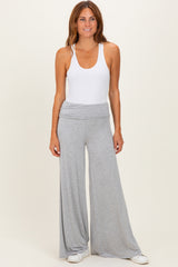 woman wearing a white tank top and light grey wide-leg pants, standing against a neutral background