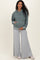 woman wearing a green maternity hoodie and gray wide-leg sweatpants, holding her baby bump